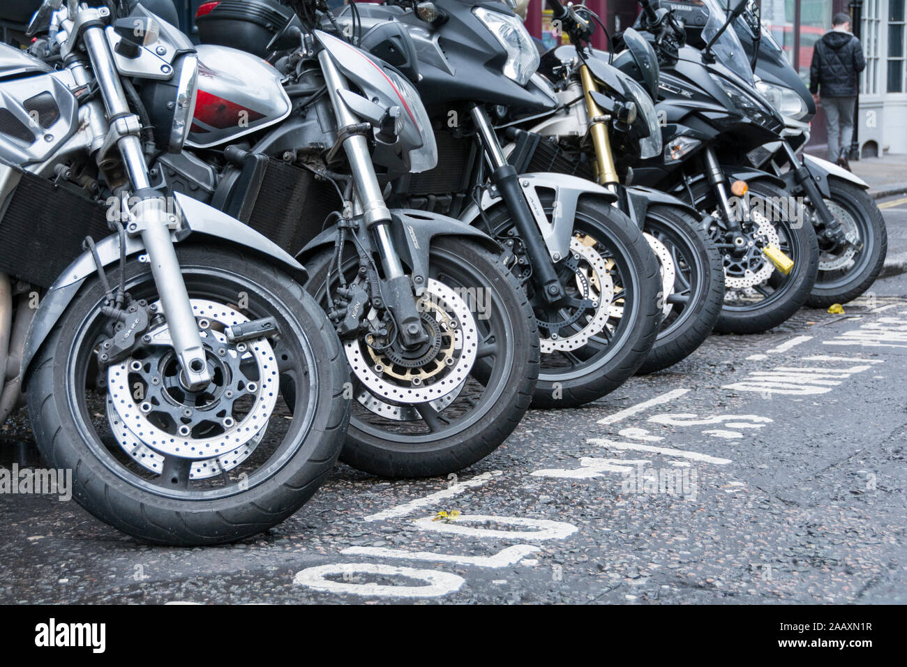 A row of motorbike tyres, forks, front wheels and brake disks on a