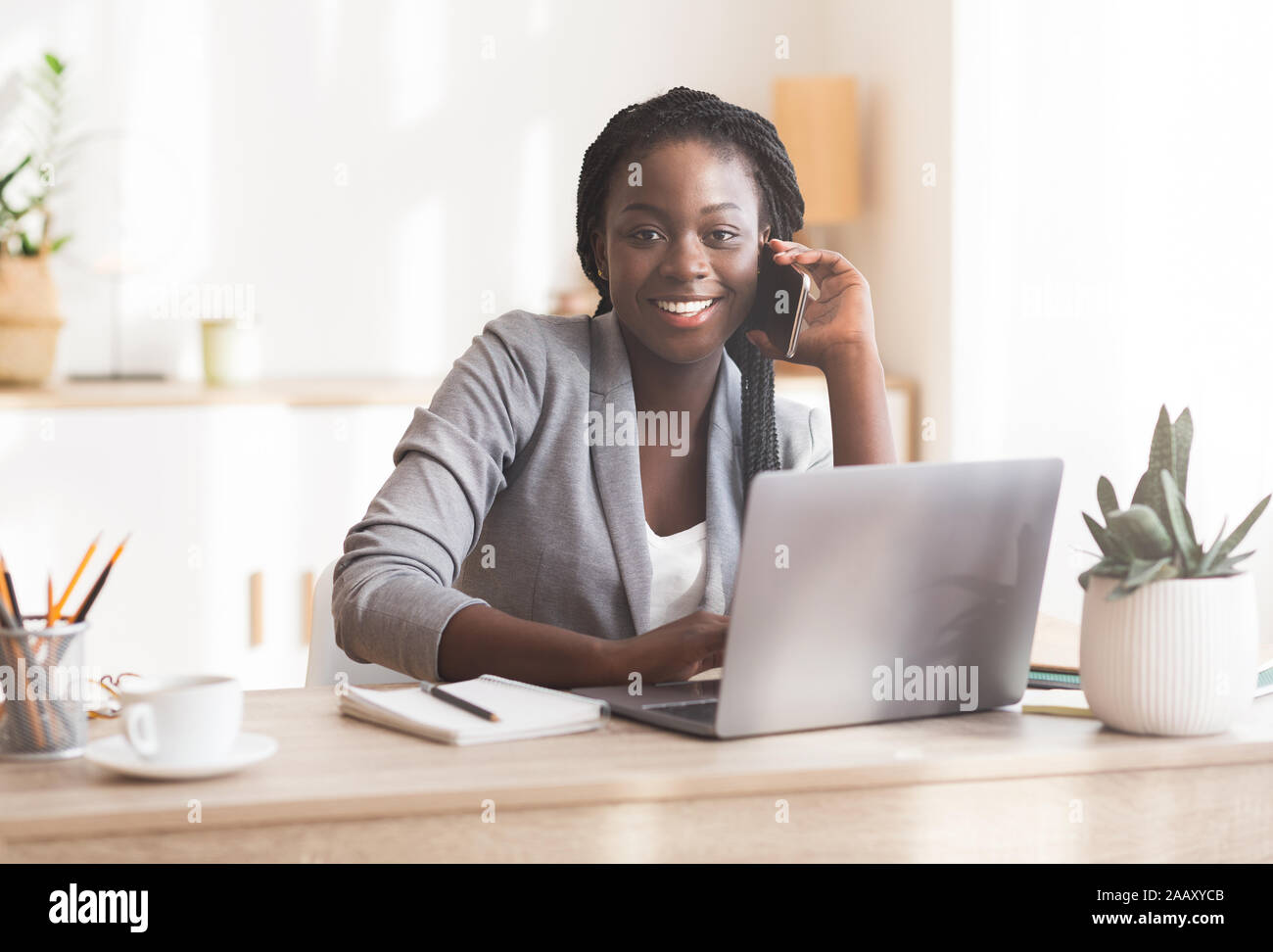 Smiling african female manager talking on cellphone consulting client Stock Photo