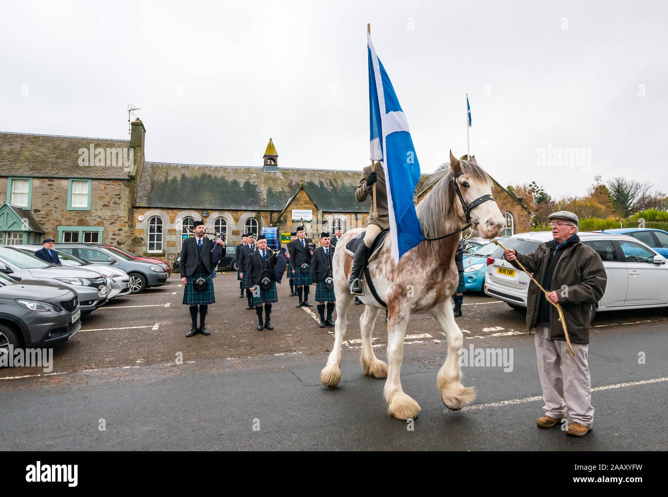 Athelstaneford, East Lothian, Scotland, UK. 24 November 2019. Saltire Festival: The first day of the annual festival to mark St Andrew’s Day takes place in the birthplace of the Scottish national flag where the saltire appeared in the sky as a good omen when the Picts & Scots defeated the Saxons led by Athelstan. Pictured: Craig Donnelly on a Strawberry Roan Clydesdale mare with groom/owner Arthur Greenan with Haddington Pipe Band Stock Photo
