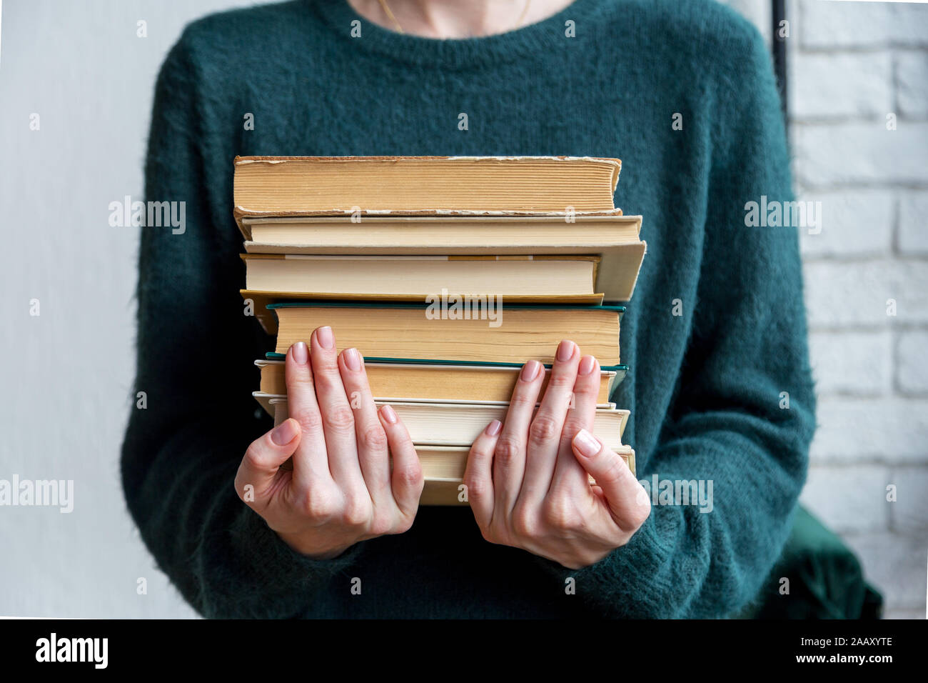 A stack of books in women's hands. Girl holds stack of old books. Concept of picture of smart women with books Stock Photo