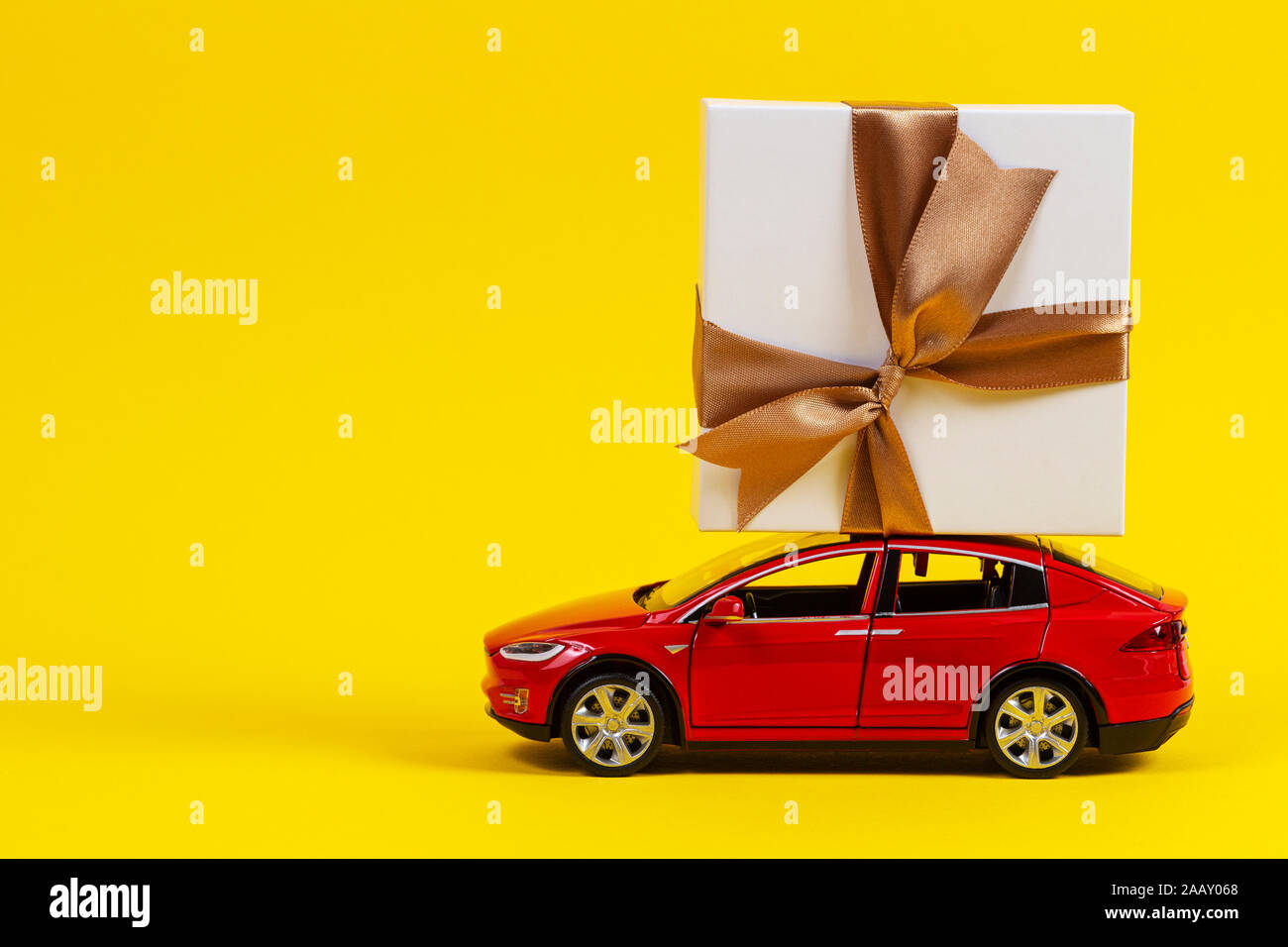 Red toy model car with present gift box on the top, yellow background Stock Photo Alamy