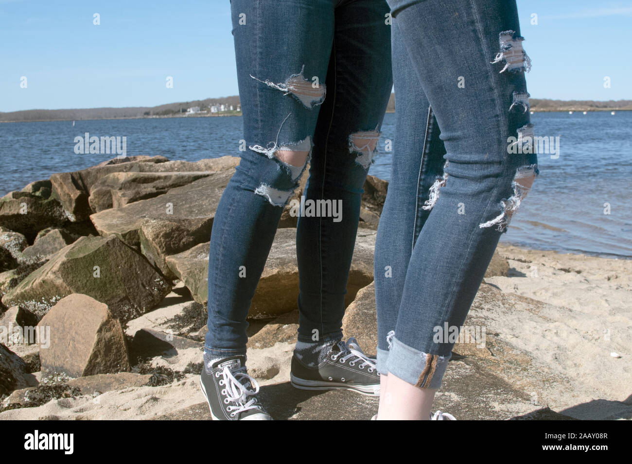 Girls with ragged jeans on rocks Stock Photo - Alamy