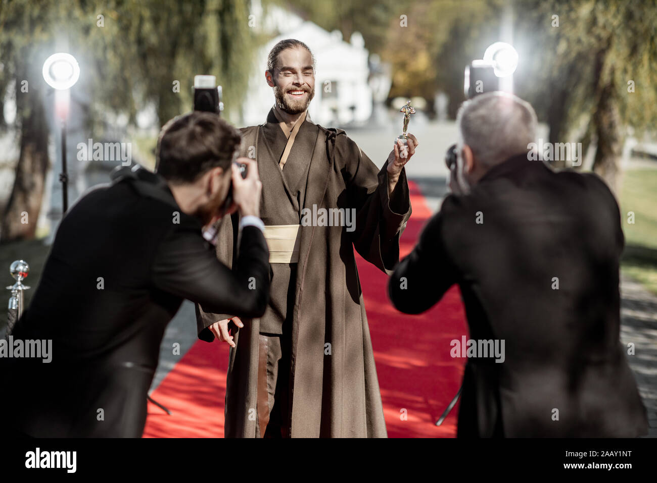 Man in costume as a well-known film character walking with annoying photo reporters on the red carpet during awards ceremony Stock Photo