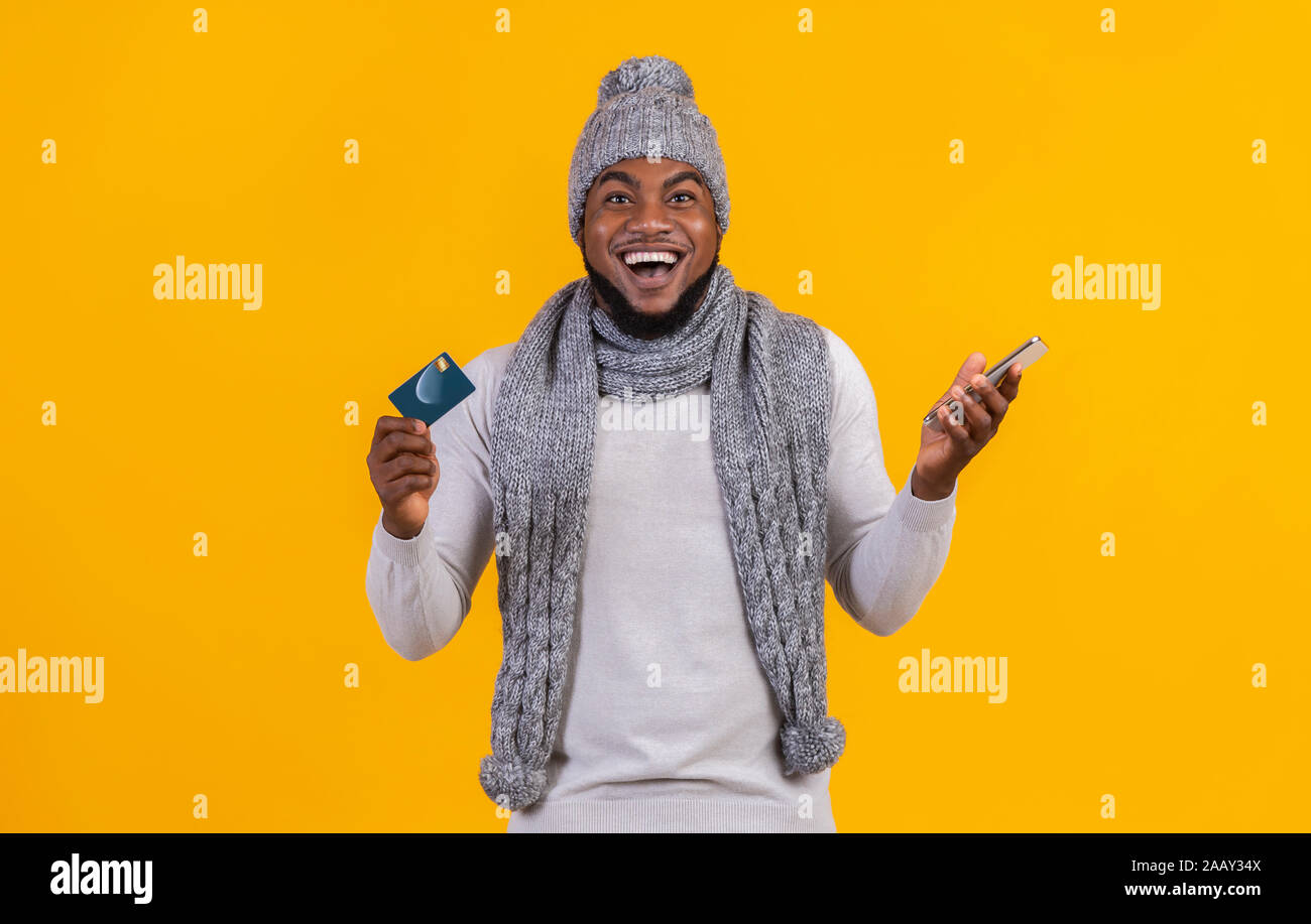 Cheerful afro man recommending credit card for shopping online Stock Photo