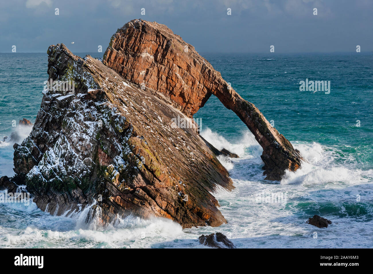 BOW FIDDLE ROCK PORTKNOCKIE MORAY SCOTLAND WINTER SCENE WITH SNOW ON THE ROCK AND A STORMY SEA Stock Photo