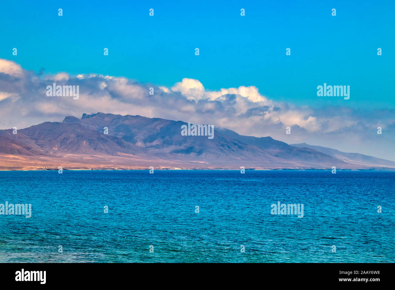 View of the hill on the island Fuerteventura near Morro Jable, Canary islands, Spain. There is clear blue water and beautiful sky. Stock Photo