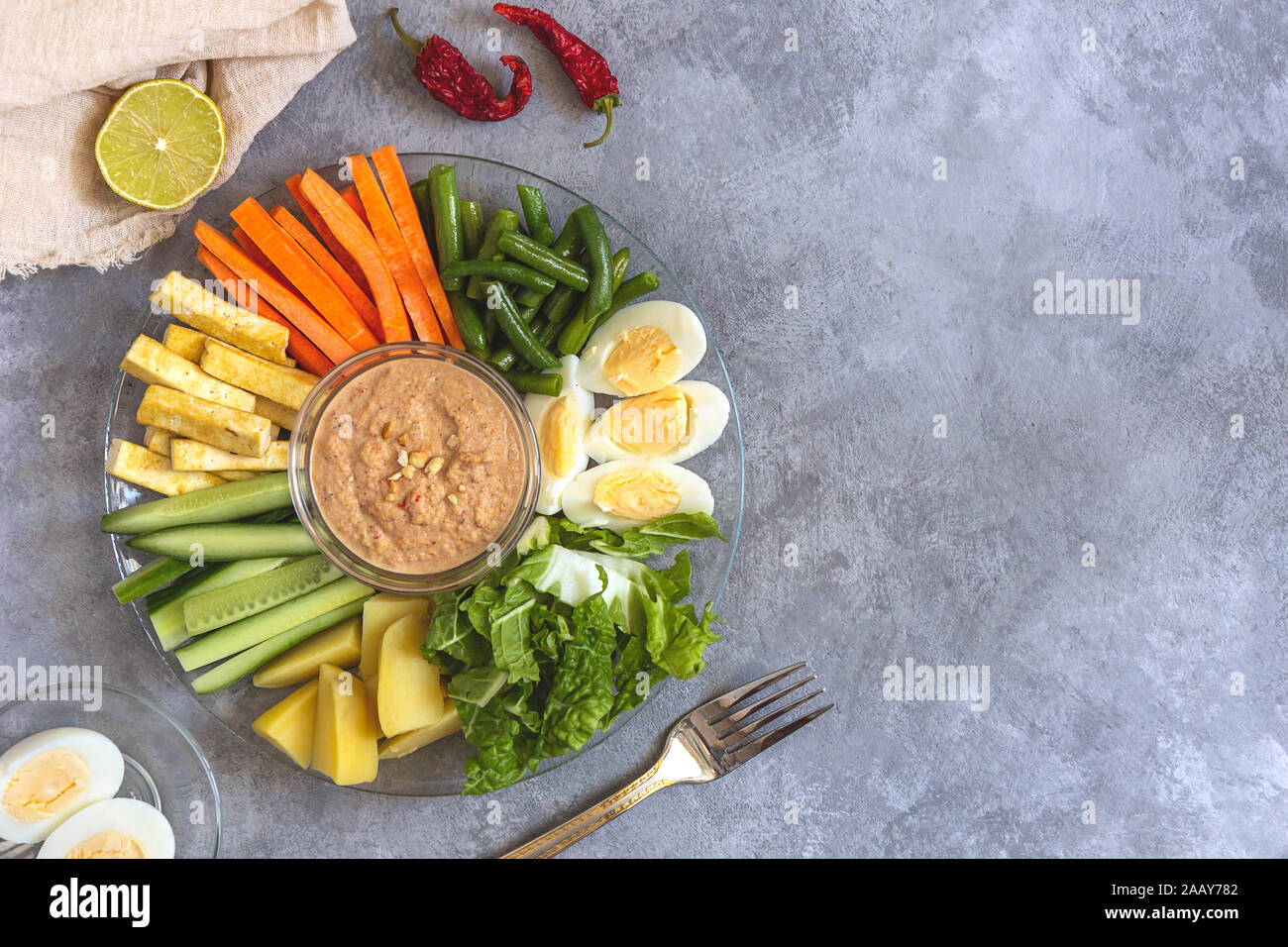 Gadogado salad with peanut sauce from Indonesia on a gray concrete