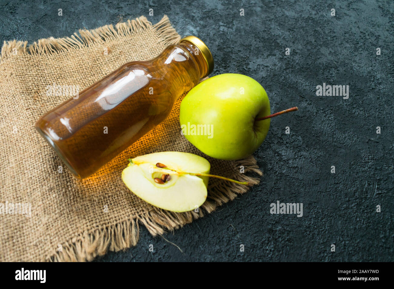 Apple juice in a bottle and a green apple on a black background. Flat lay. Copy space. Stock Photo