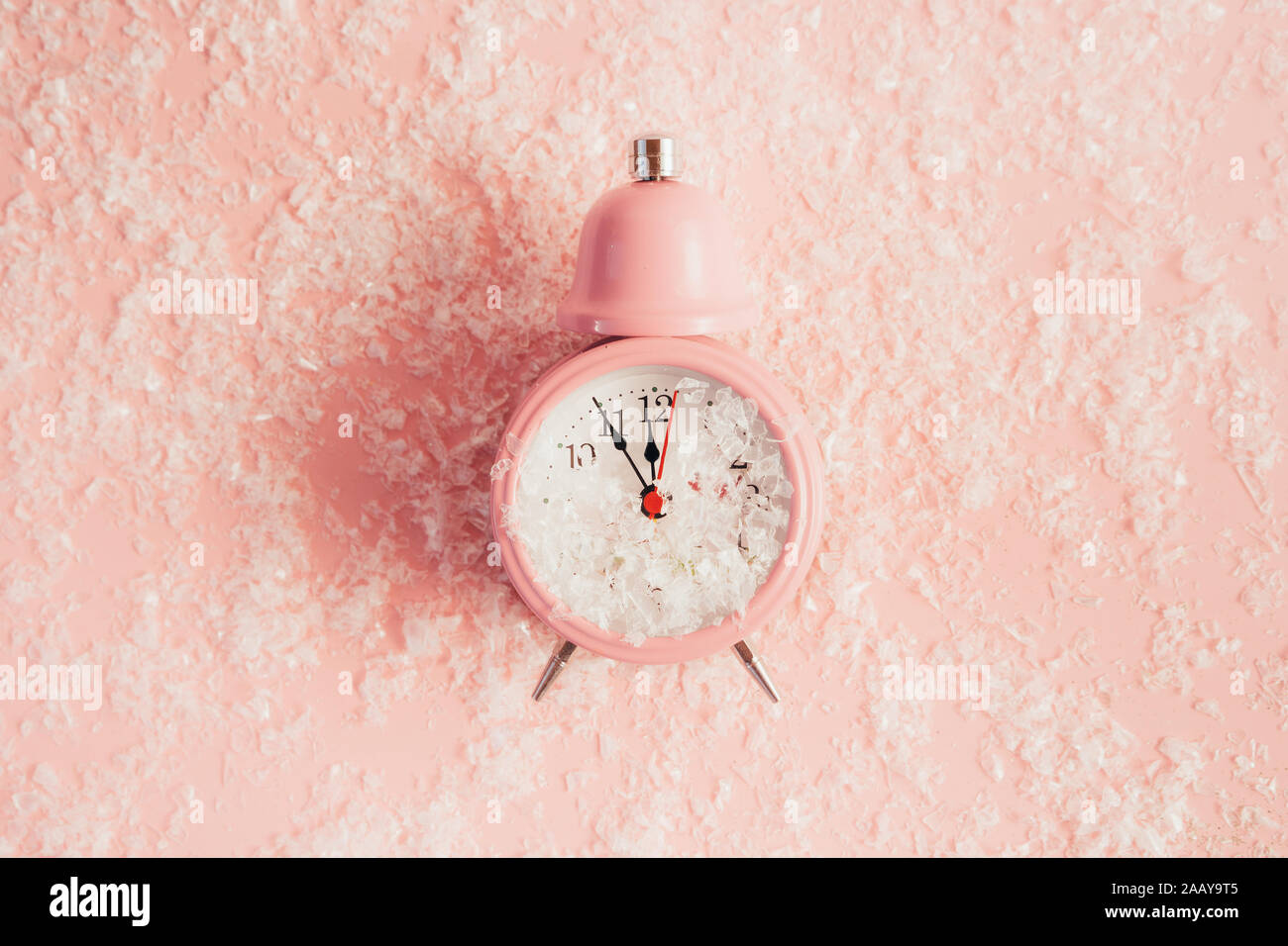 Alarm clock showing five minutes to midnight on pastel pink color Stock
