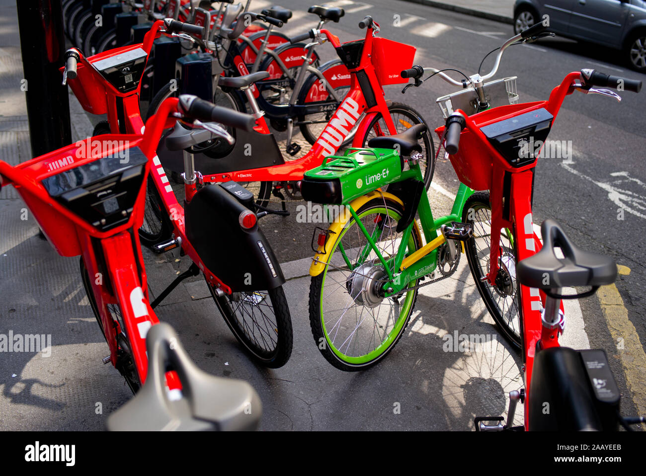 A Lime-E and Jump electric assistance cycle sharing station with bikes parked up in the with the vibrant colours standing out in the early morning sun Stock Photo