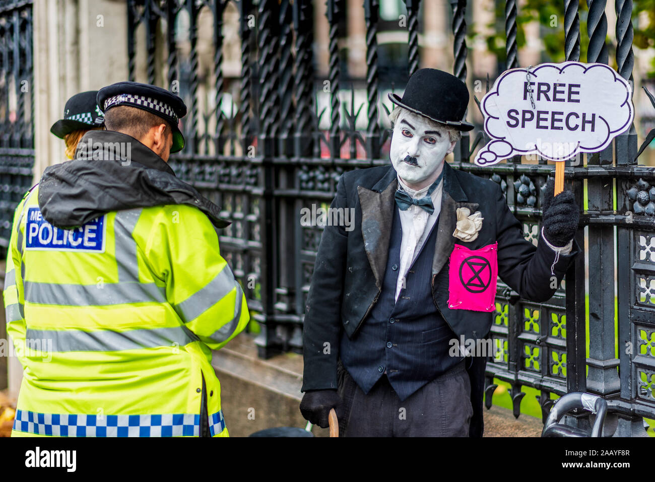 Free Speech UK Parliament. Police question an Extinction Rebellion protester dressed in Chaplin type clothes outside the Houses of Parliament London. Stock Photo