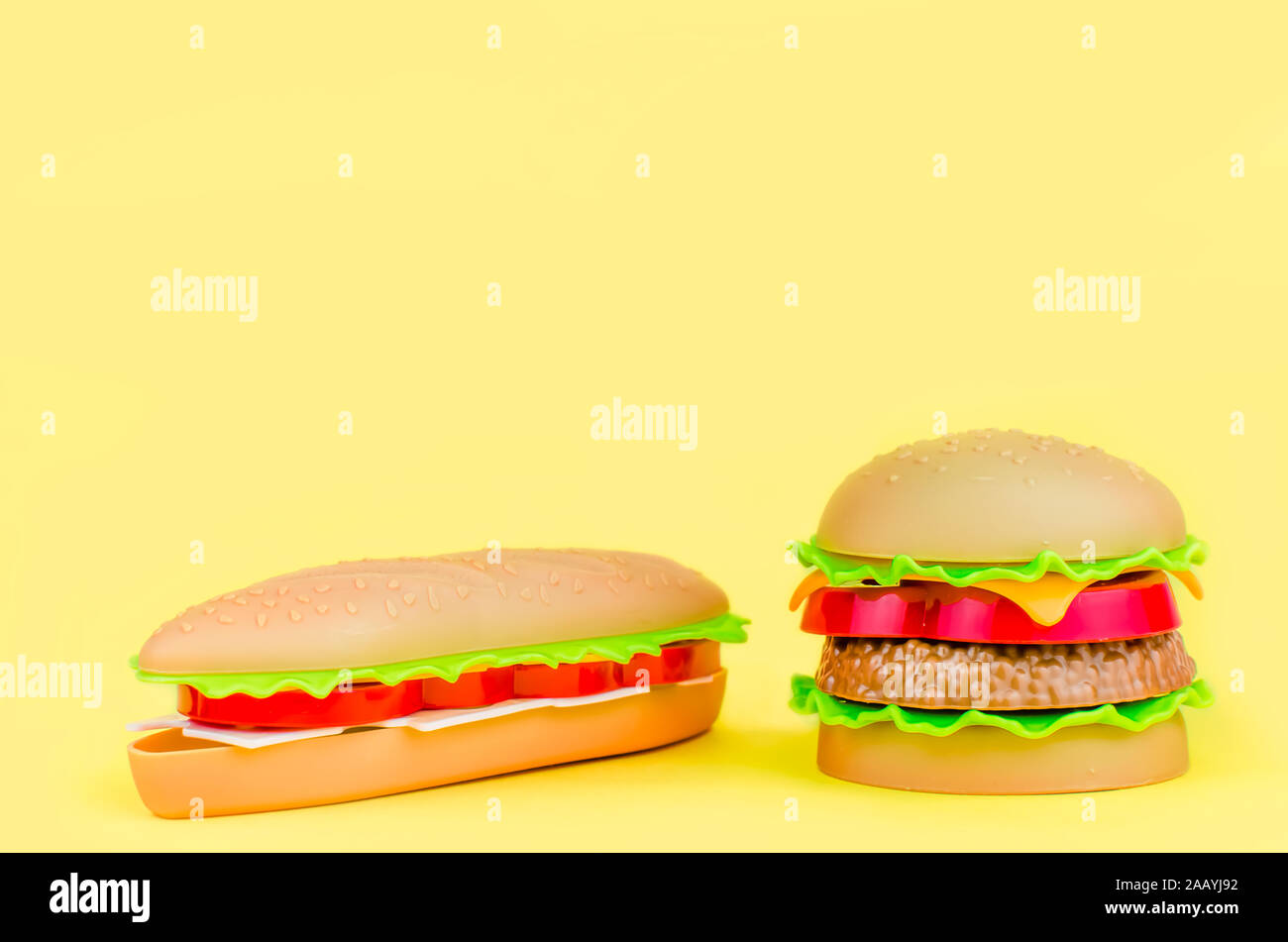 fast food. plastic hamburger, hot dog on a yellow background Stock