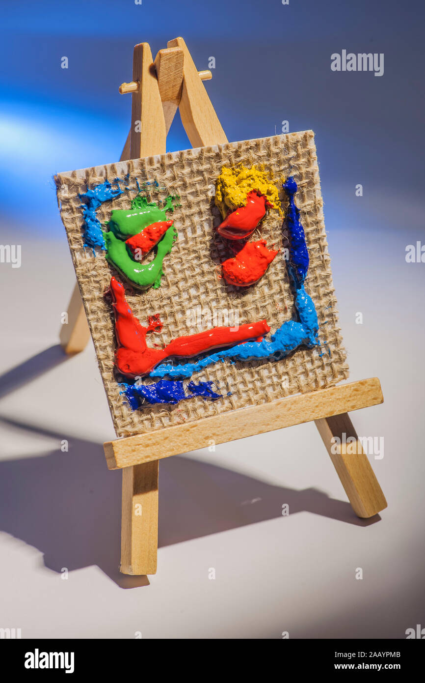 Still life of a canvas with colorful pasty paint blobs on a miniature