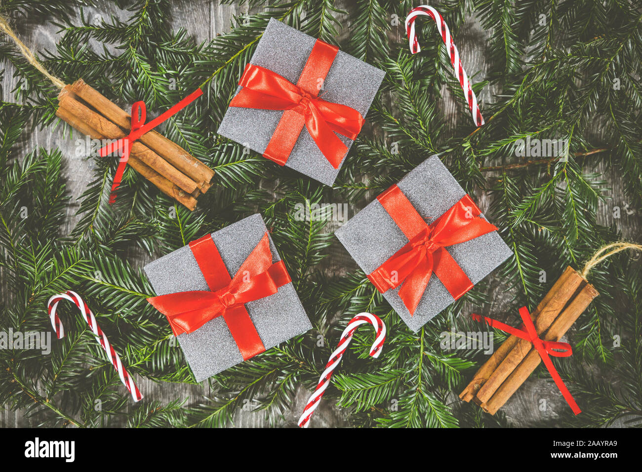 Three Christmas presents sat on the branches of a Christmas tree along side candy cane and cinnamon stick decorations Stock Photo