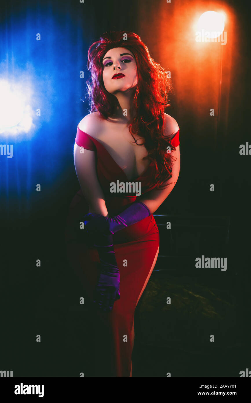 Glamorous woman in long red dress and purple evening gloves in a smokey club Stock Photo