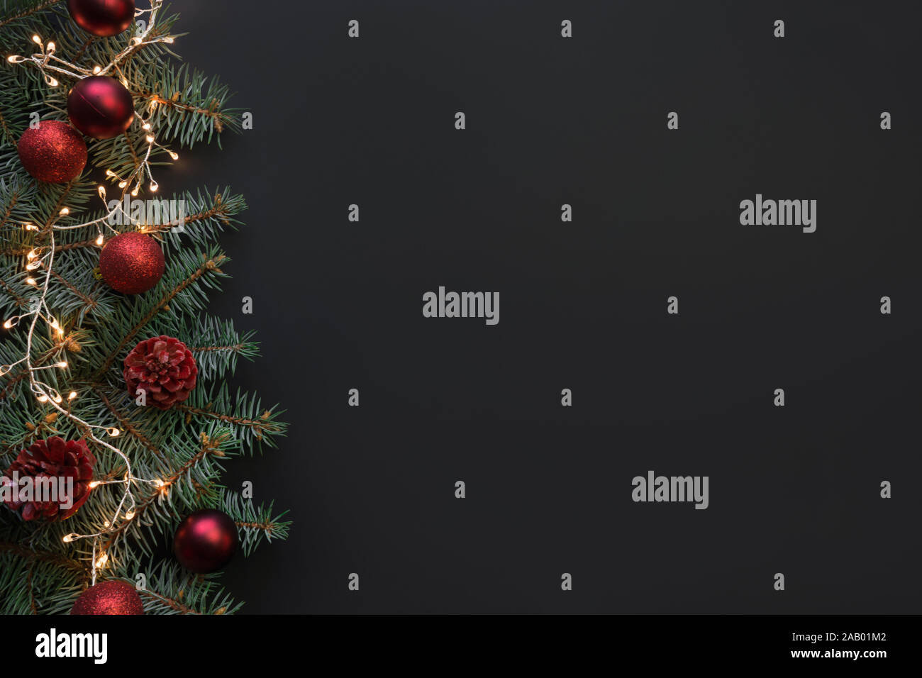 Christmas frame with fir branches, red balls, garland on black ...