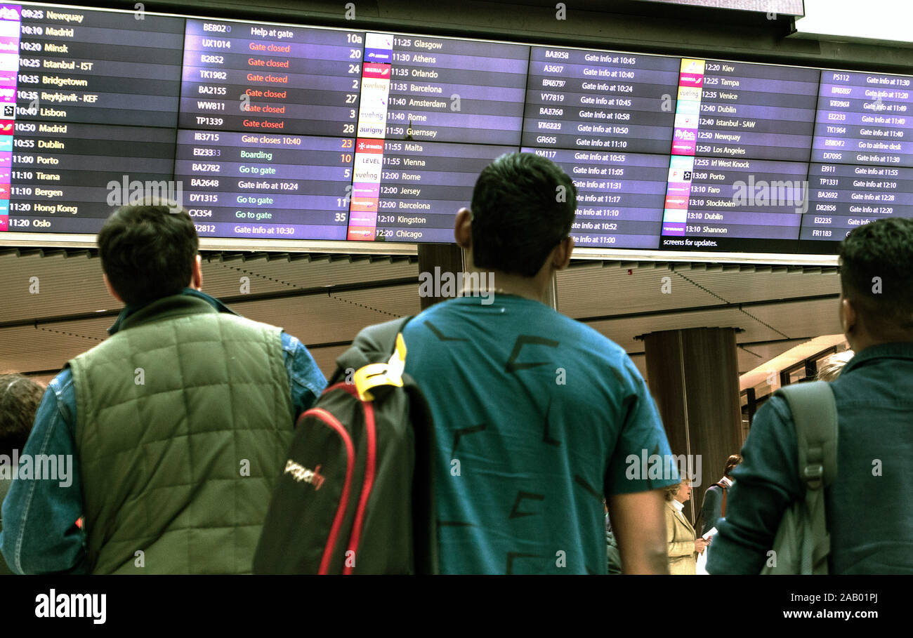 Passengers look at flight departures board Gatwick Airport London UK Stock Photo