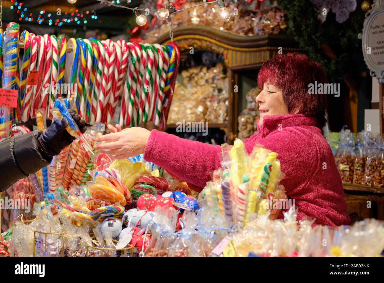 Lady Food Vendor In A Candy Shop Handing Over Sweet Treats Just Purchased To The Gloved Hand Of A Faceless Customer At Strasbourg Christmas Market Stock Photo Alamy