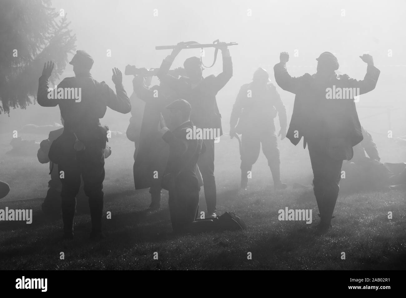 Silhouettes of Soldiers in uniforms during War with rifles on battlefield. All area is in smoke and sunrays peeking thru. There are hostages in the Stock Photo