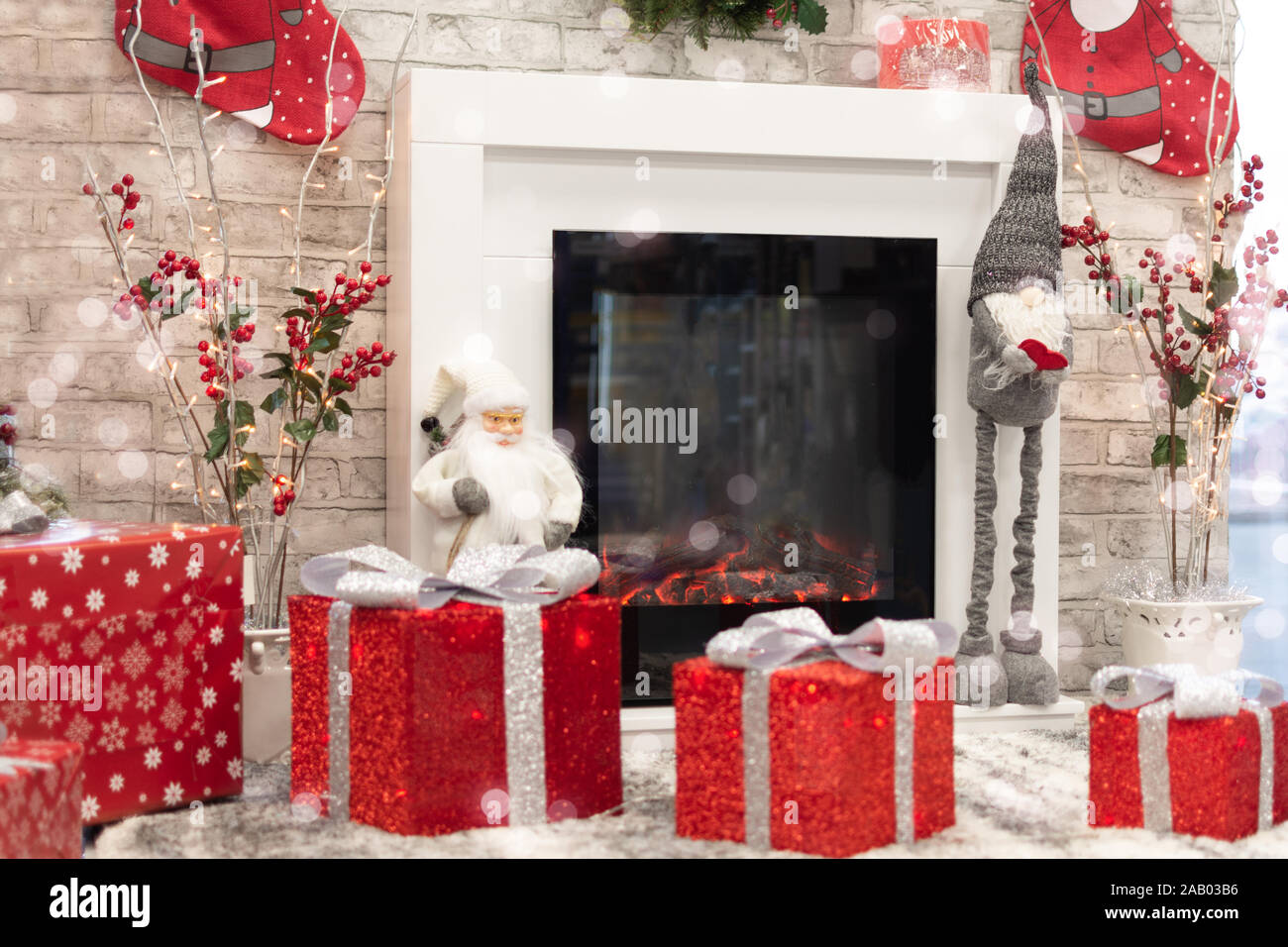 New Year home decorated with gift boxes, red wrapping Santa presents and Christmas decorations. Living room with fireplace decorated for Christmas hol Stock Photo