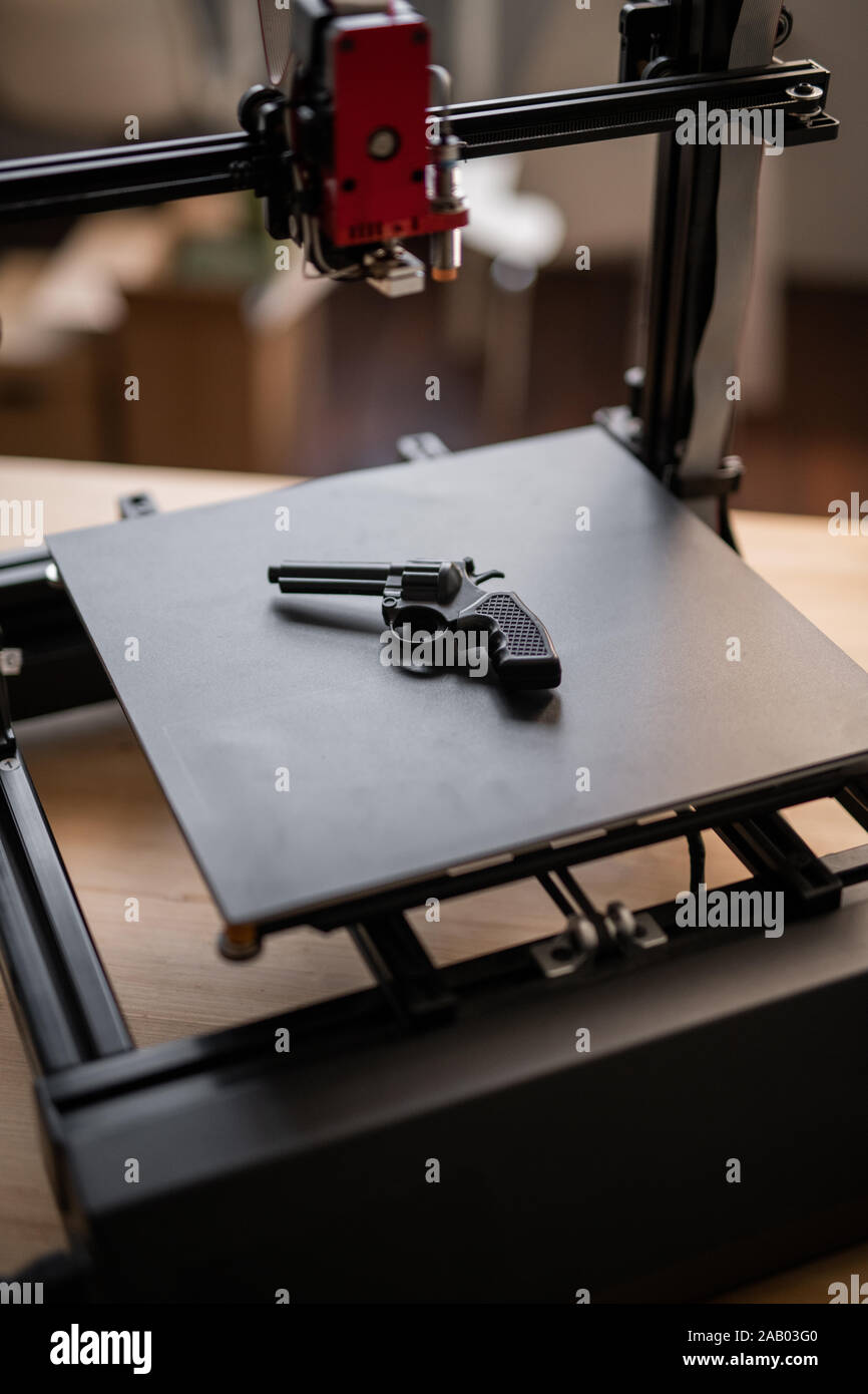 Black revolver gun lying on working surface of modern 3d printer with  printhead hanging above Stock Photo - Alamy
