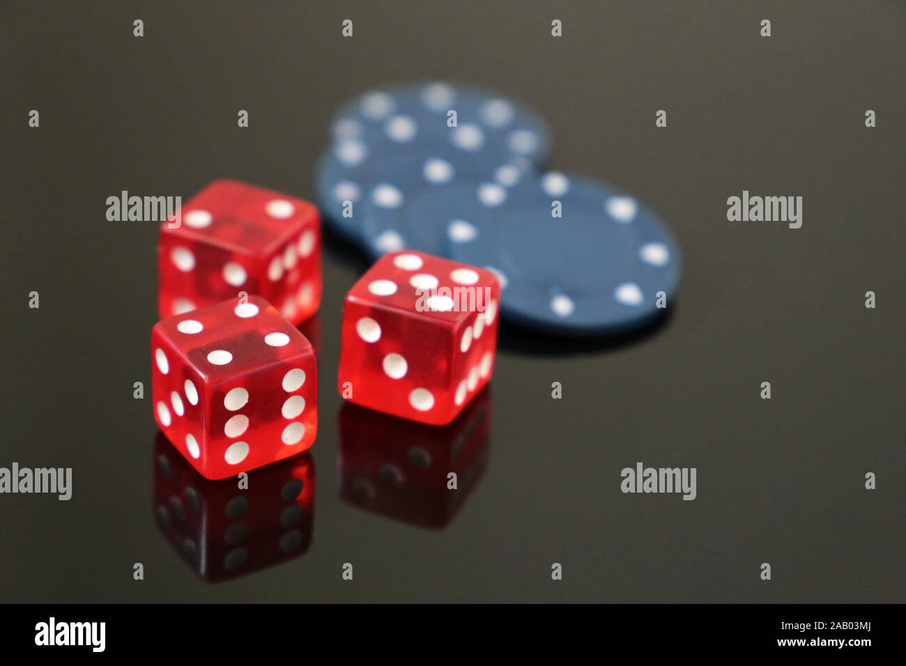Red dice and casino gaming chips on dark mirrored table. Background for casino games, gambling, luck or randomness Stock Photo