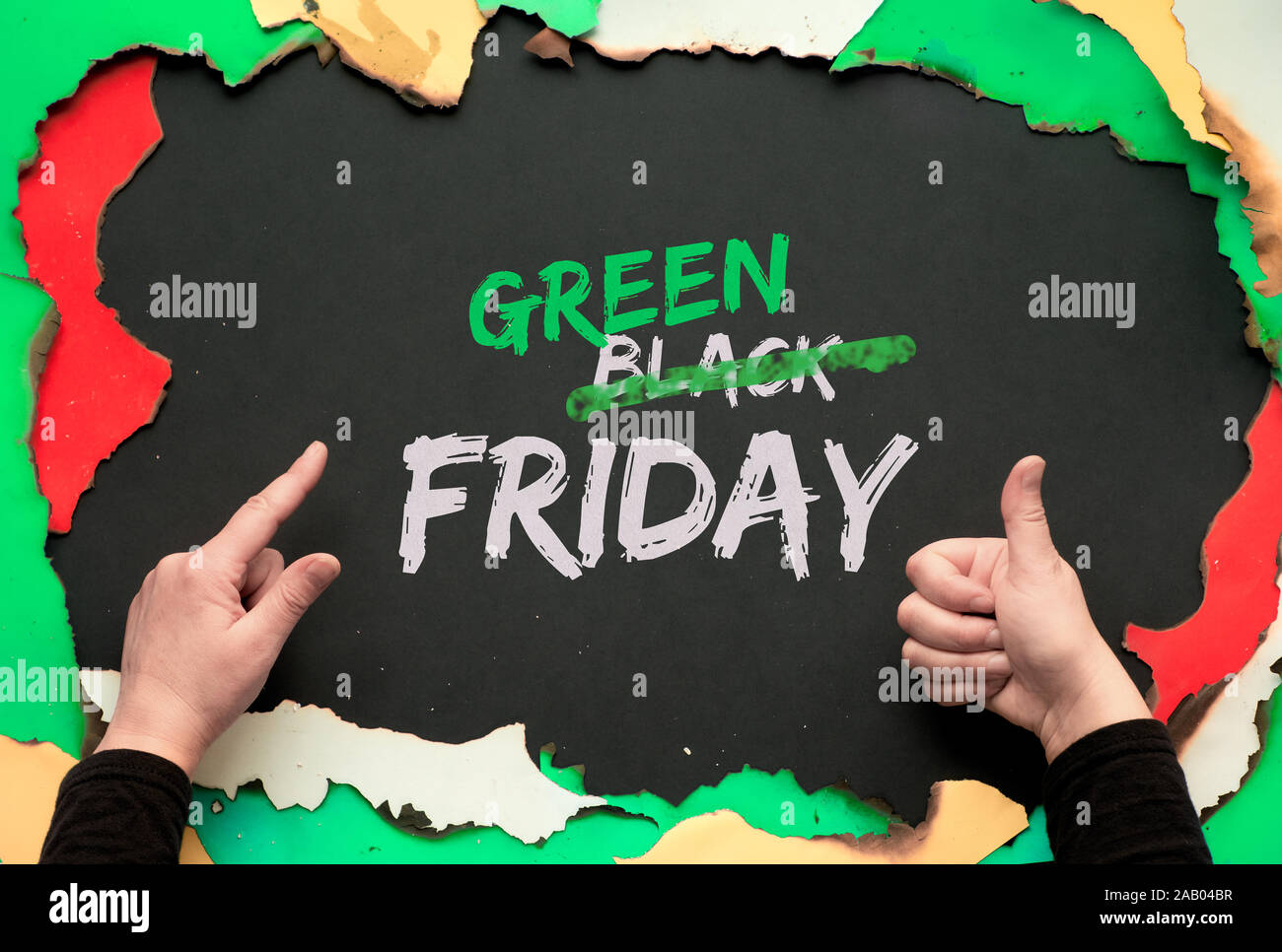 Green Friday, burnt frame with burned color paper. Hands showing OK sign and pointing index finger.Text 'Black Friday Sale'  with word 'Black' crossed Stock Photo