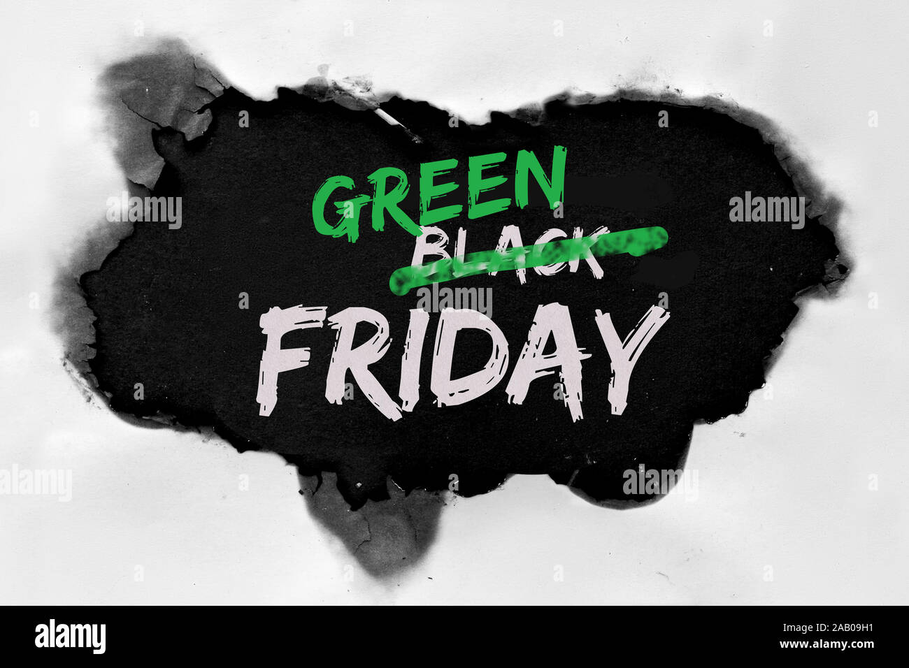 Green Friday concept with hole burned in white paper. Text 'Black Friday Sale'  with word 'Black' being crossed out. Strikethrough or strikeout effect Stock Photo