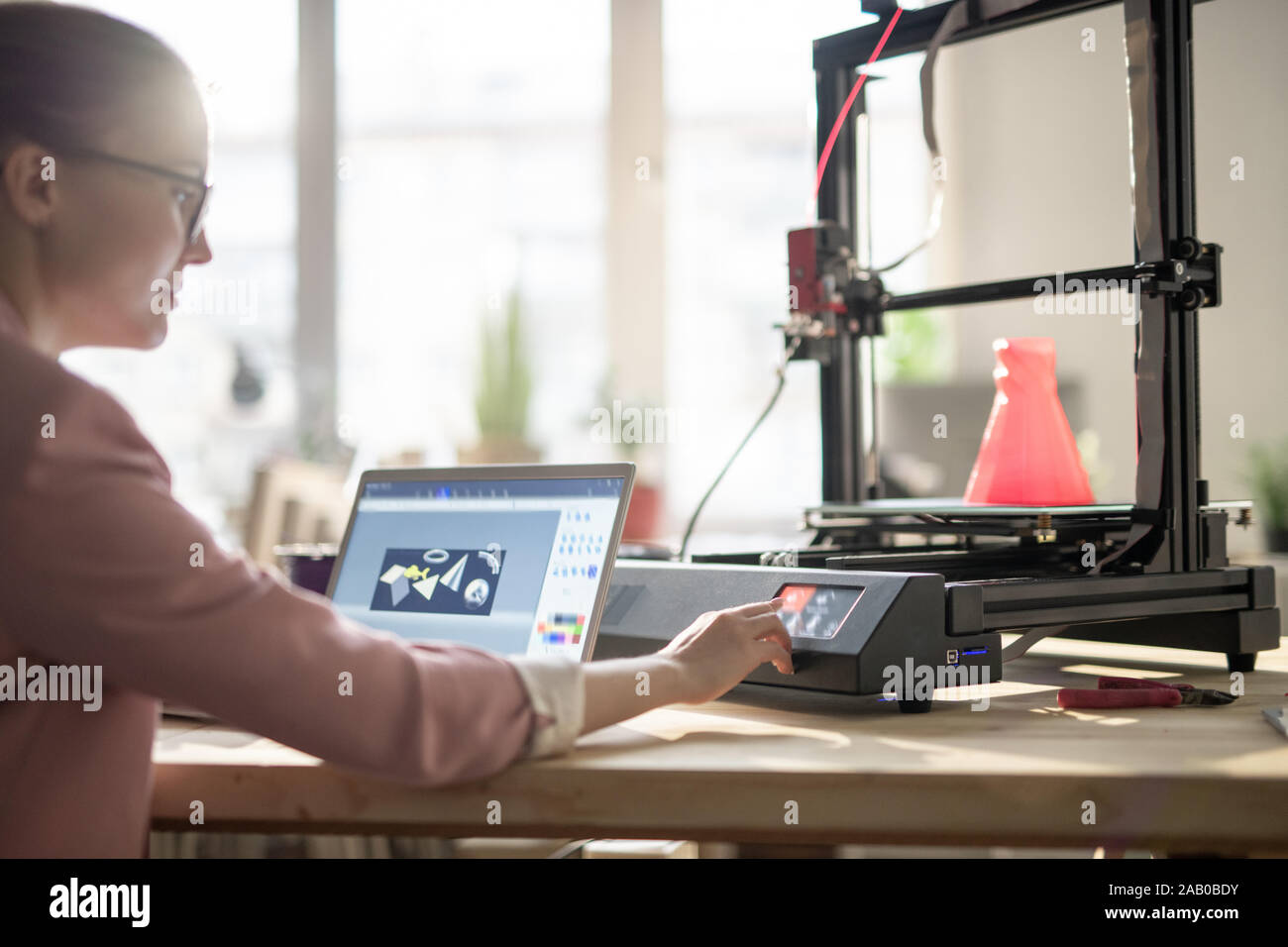 Creative female designer pushing button on control panel of 3d printer Stock Photo