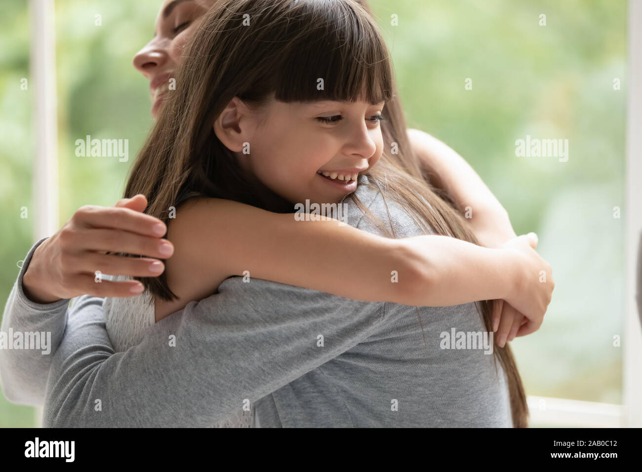Loving mother strong cuddling little cute daughter closeup image Stock Photo