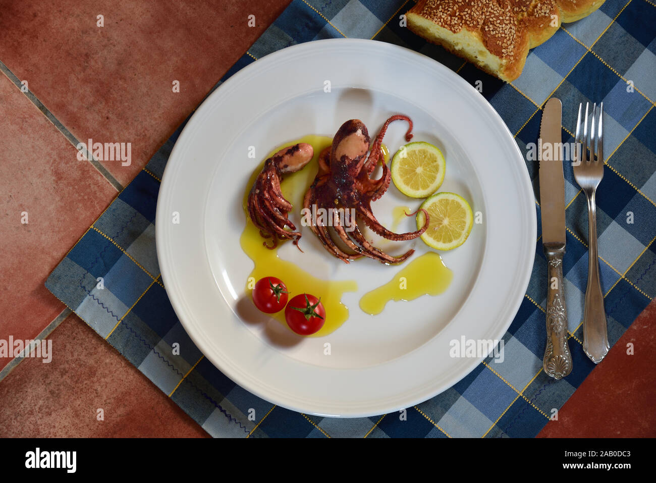 A plate of cooked small polyp and lemons garnished in olive oil on a ...