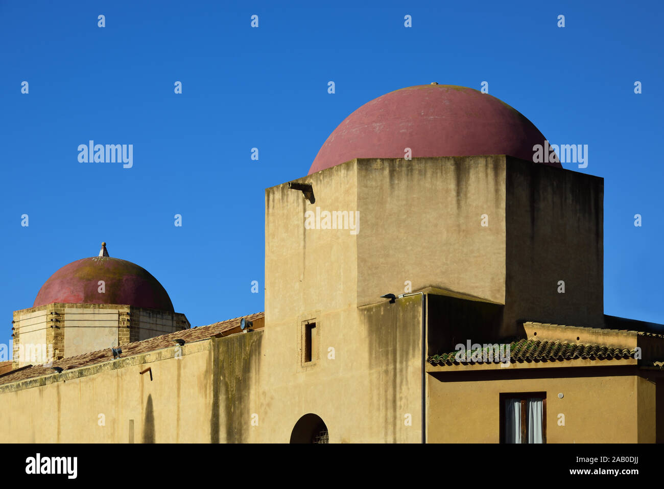 Historic towers with red round domes in the old town of Mazara del Vallo, Sicily, Italy against a blue sky in summer Stock Photo