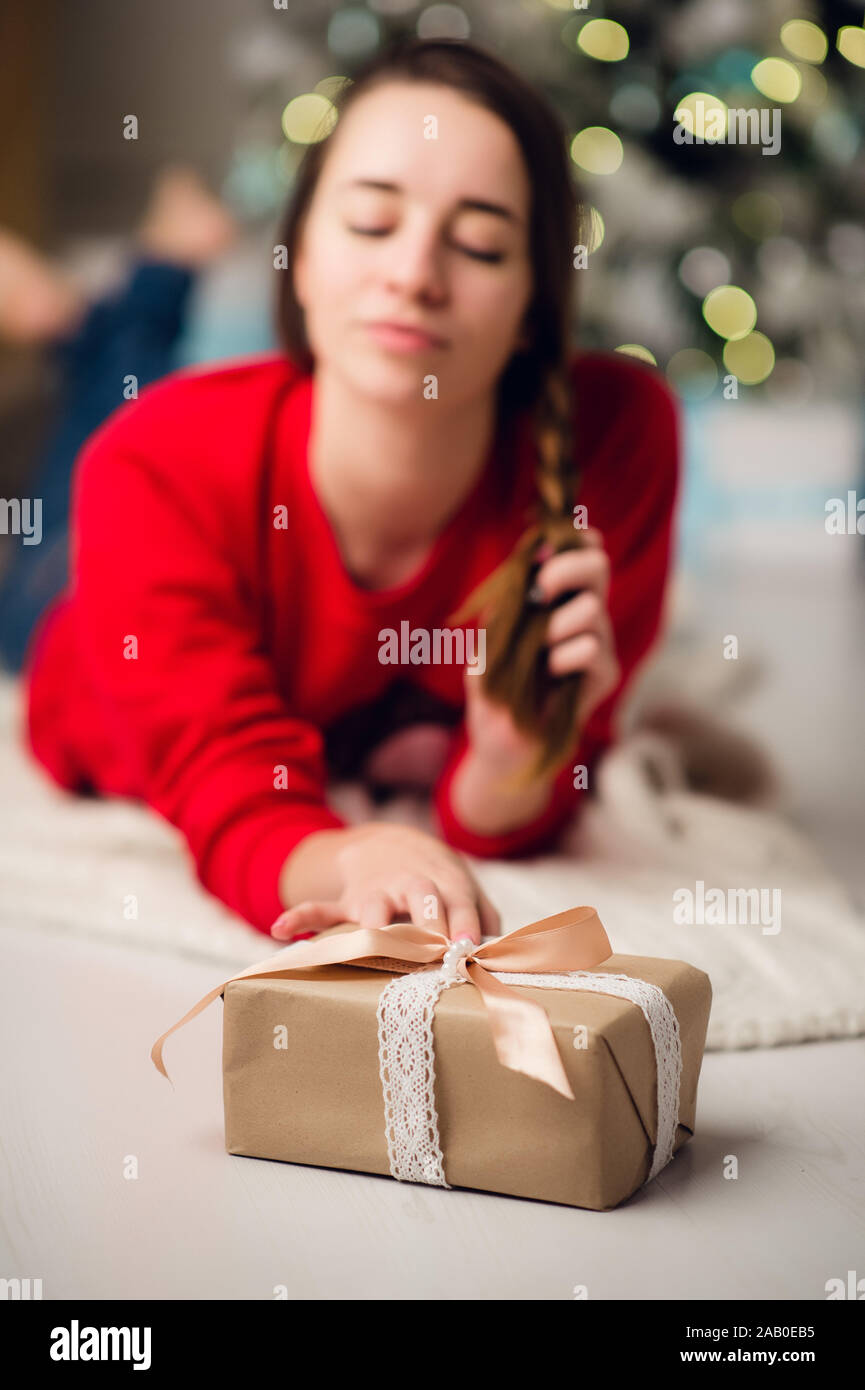 Low below angle view photo of charming cute beautiful attractive girl with a gift wearing jeans and red sweater Stock Photo