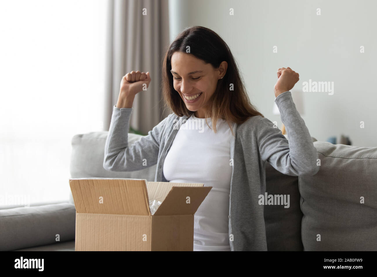 Cheery woman received long-awaited carton package feels happy Stock Photo