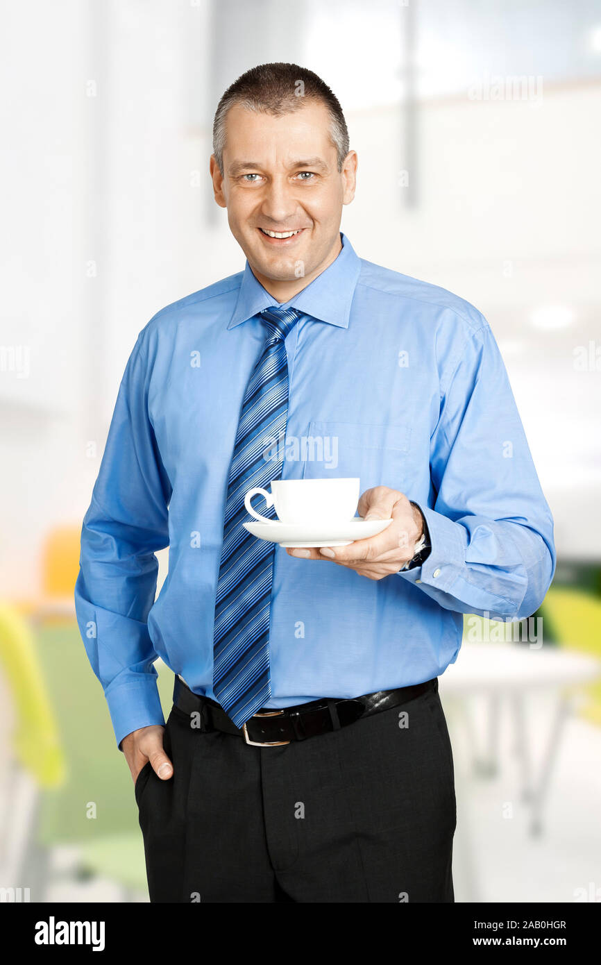 Ein laechelnder Geschaeftsmann mit einer weissen Kaffeetasse in der Hand Stock Photo