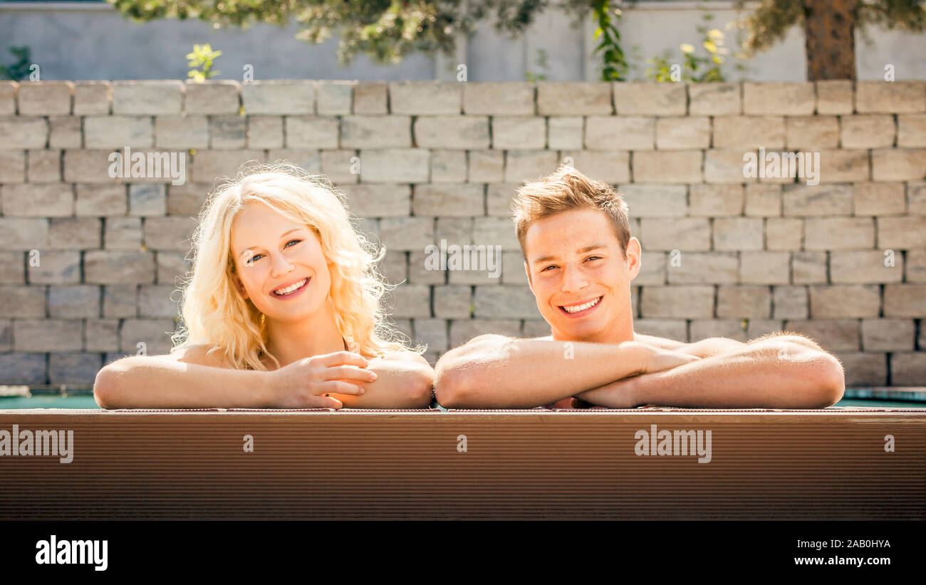 Ein junges Paar, das am Schwimmbeckenrand entspannt Stock Photo
