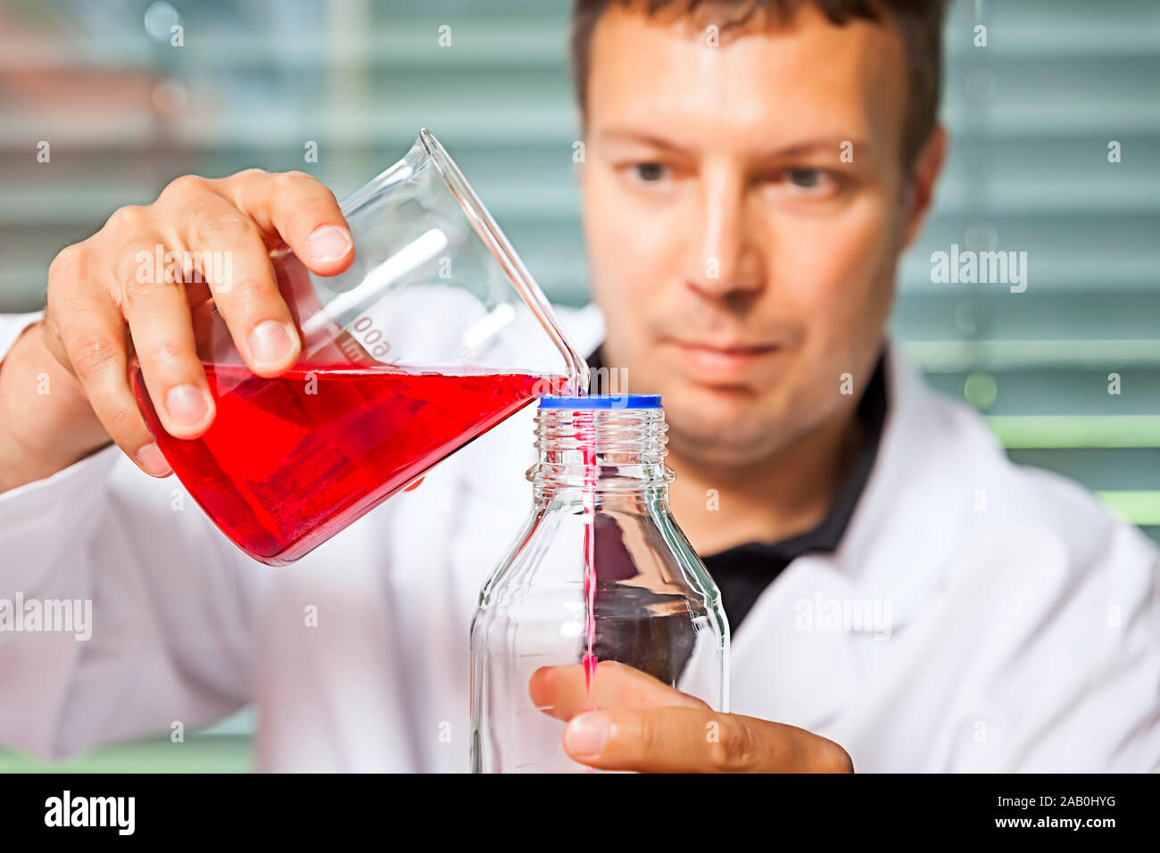Ein junger Laborant, der mit Chemikalien experimentiert Stock Photo