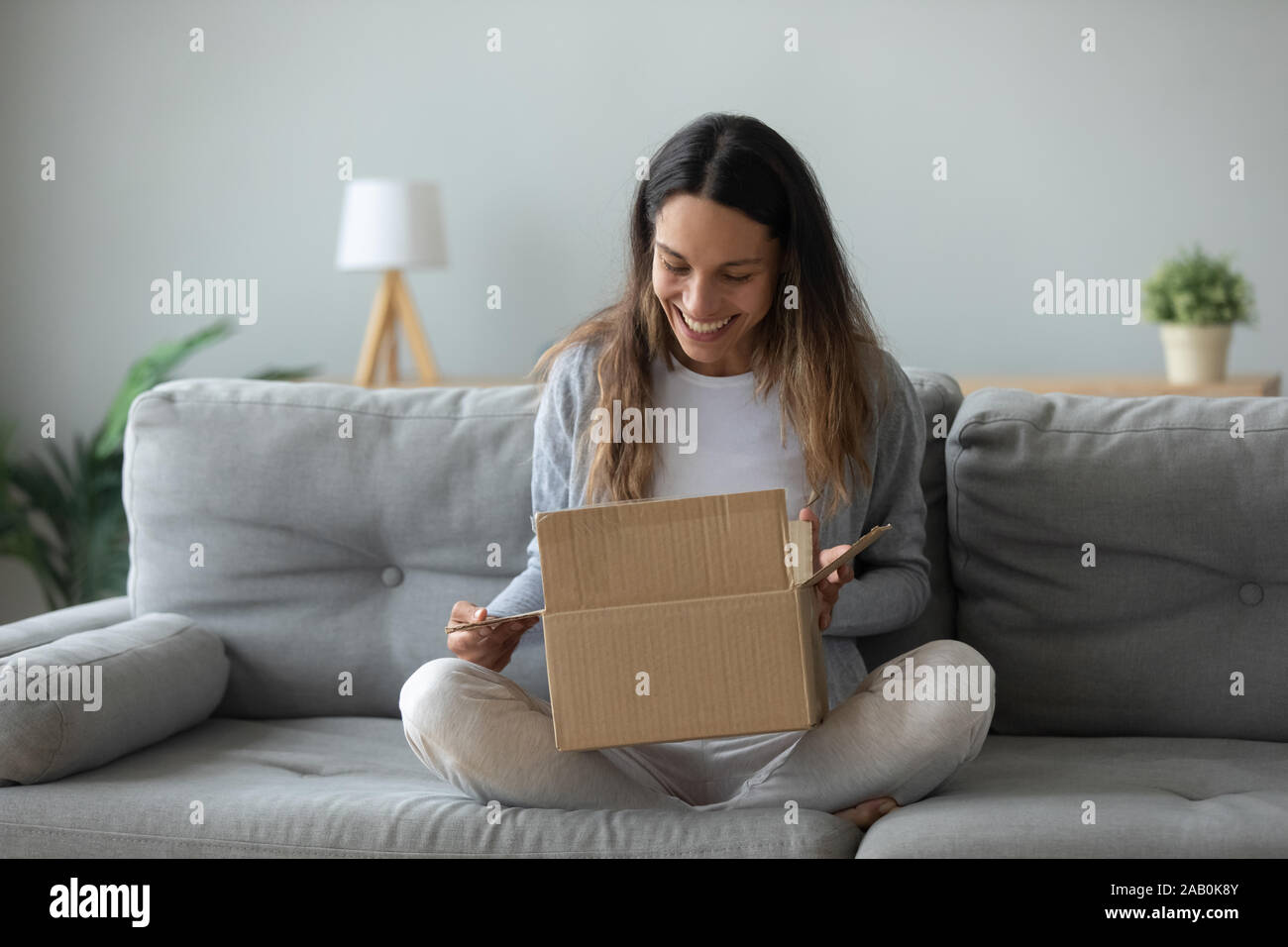Overjoyed young woman opens box parcel feels satisfied Stock Photo