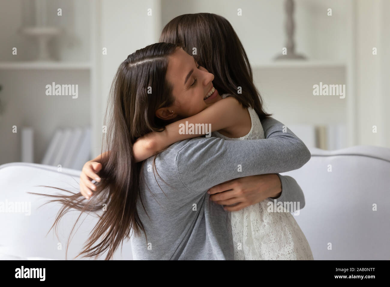 Happy young mother strong cuddles her little daughter Stock Photo