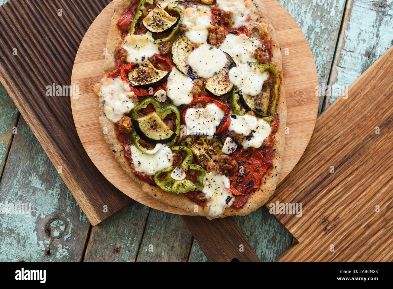 Autumn comfort food. Wholegrain rustic pizza with eggplant and mozarella served  on oak boards on old blue background overhead view Stock Photo