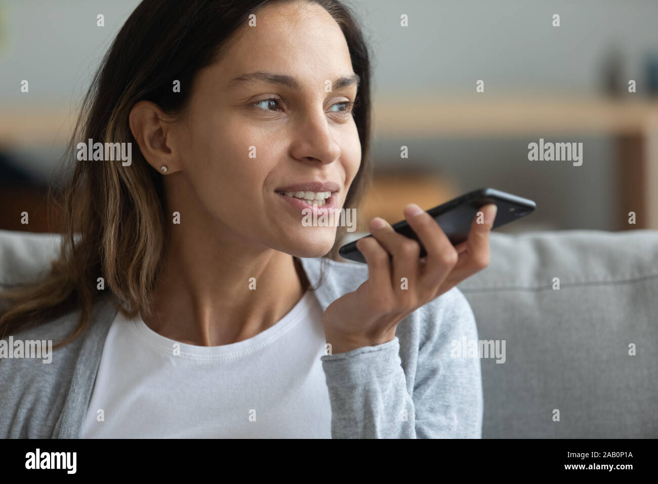 Woman holding smartphone using speakerphone or virtual assistant Stock Photo