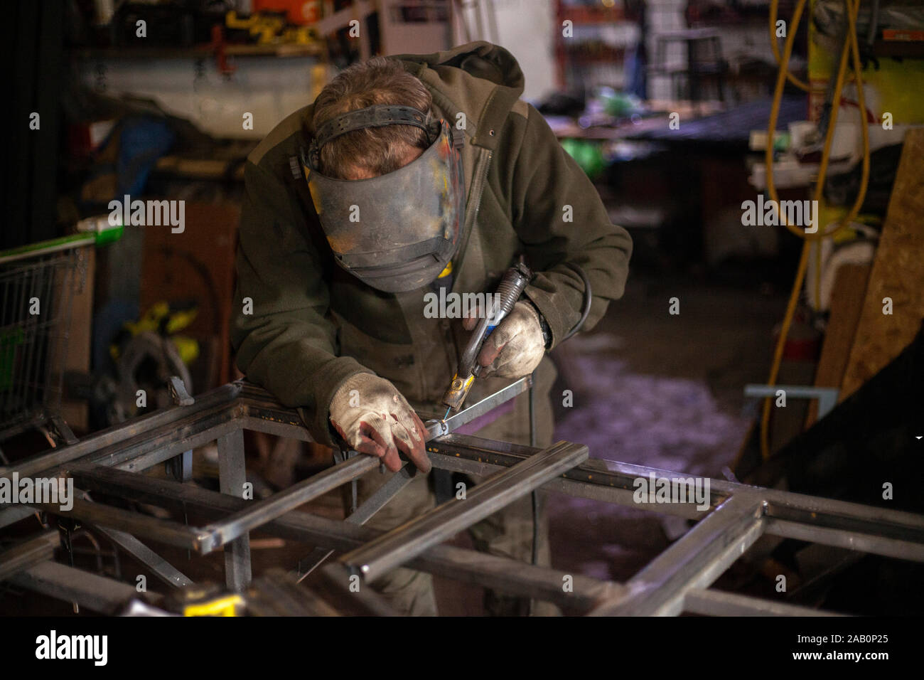 Metal welding in a workshop. A masked welder is working on a part. Creating reliable adhesion of materials. Hot metal melts when exposed to temperatur Stock Photo