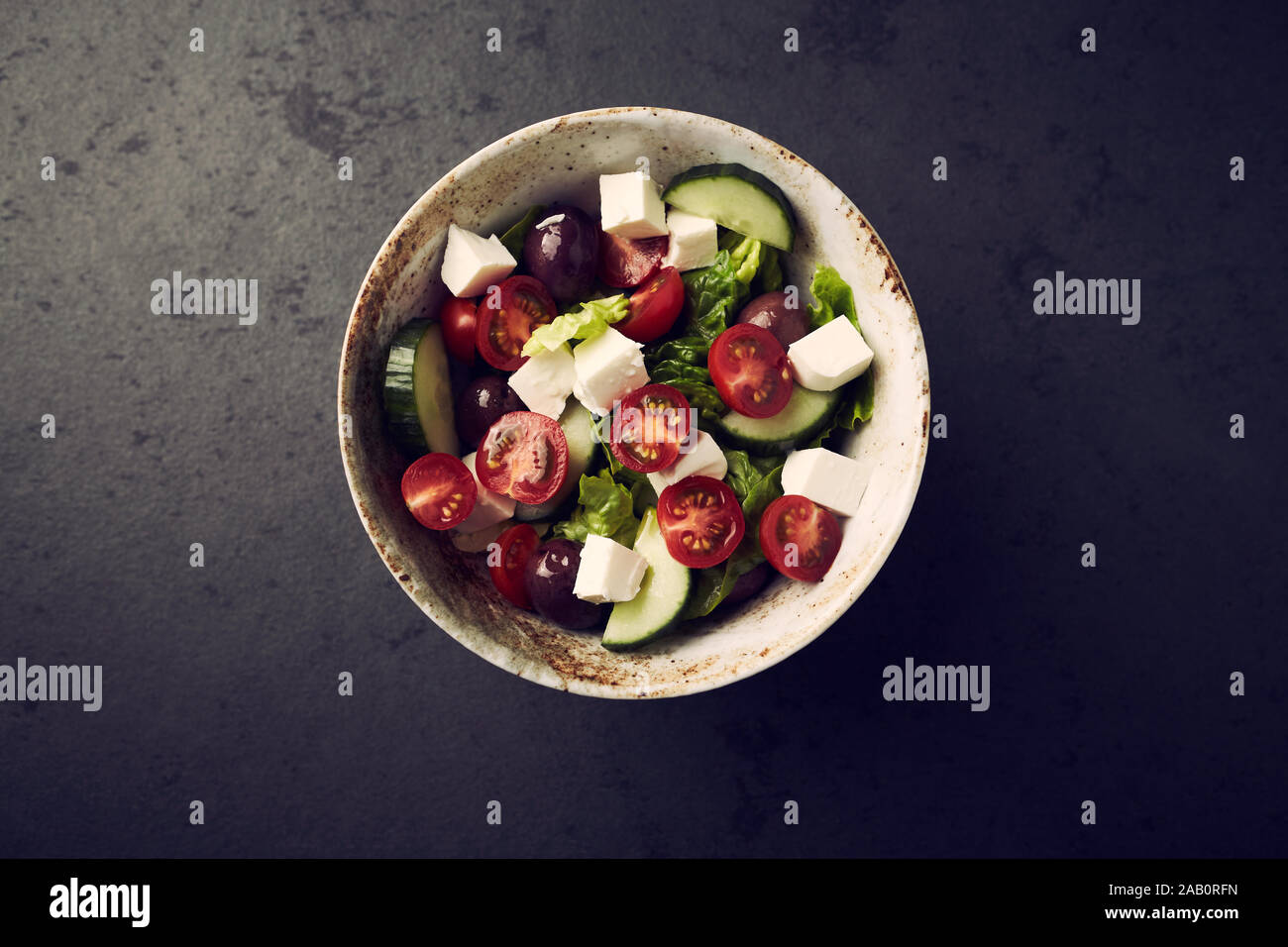 Salad with Kalamata Olives, Cucumber Cherry Tomatoes and Feta Cheese on black Stone Background. Stock Photo