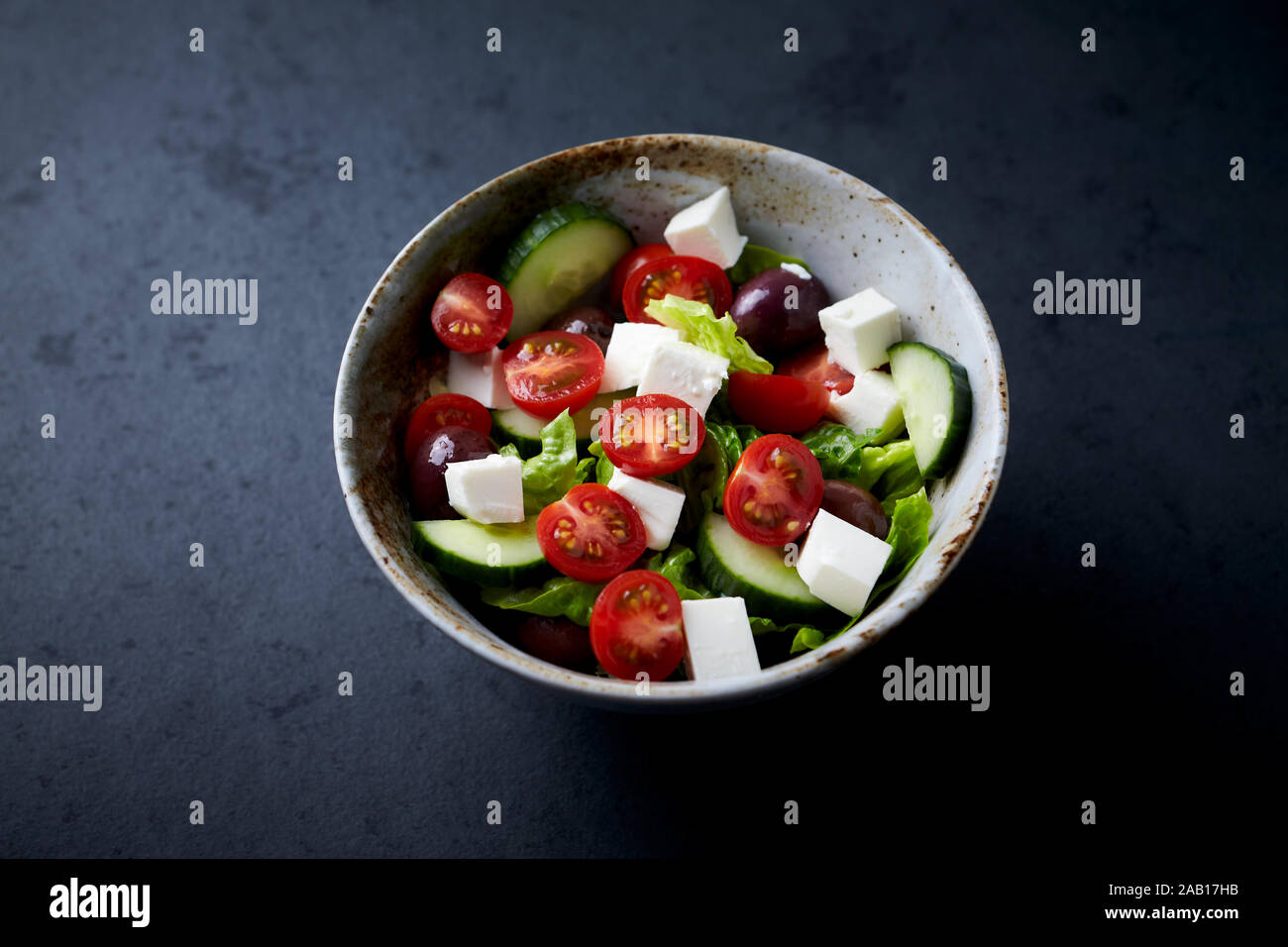 Salad with Kalamata Olives, Cucumber Cherry Tomatoes and Feta Cheese on black Stone Background. Stock Photo