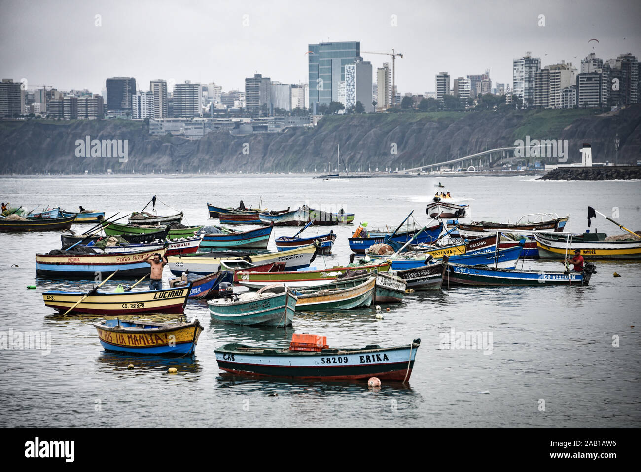 Lima, Peru - Nov 17, 2019: Fishing boats in Chorrillos harbour against the backdrop of the commercial Miraflores district Stock Photo