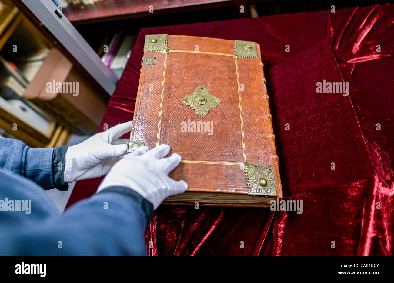 Hamburg, Germany. 19th Nov, 2019. An employee of Ketterer Kunst, a Hamburg  art auction house, leafs through a volume of a Bible from Gutenberg's  printing press, which is auctioned off in an