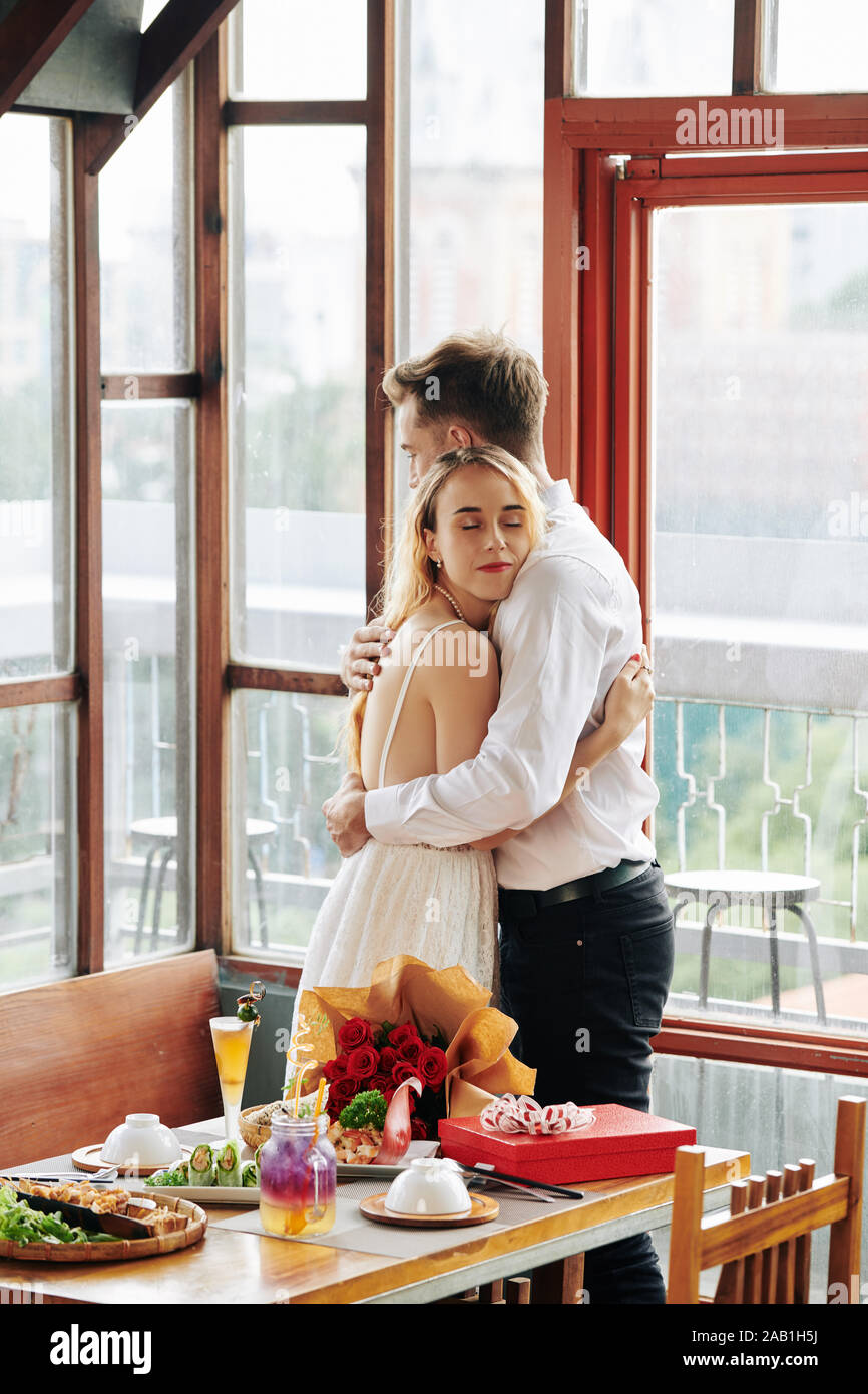 Pretty young woman hugging boyfriend after accepting romantic present ...