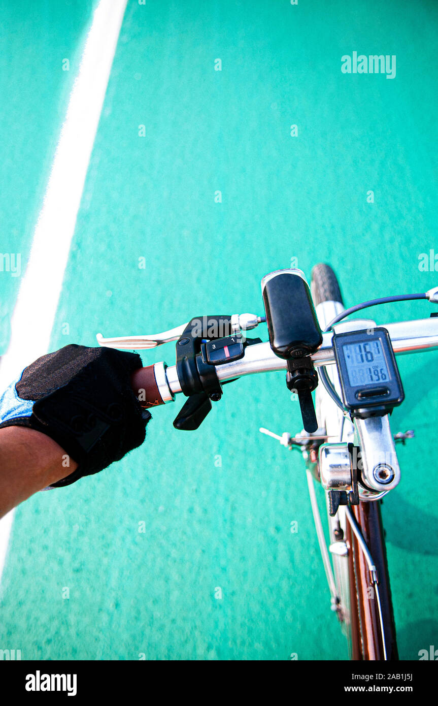 View from bicycle rider hand grabed handle bar during cycling in speed motion. Crop sport bicycle break lever and gear shifter shot Stock Photo