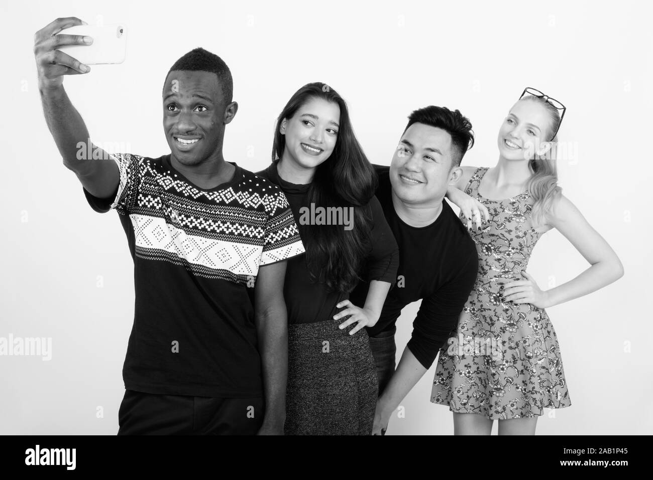 Happy diverse group of multi ethnic friends smiling and leaning on shoulder while taking selfie together Stock Photo