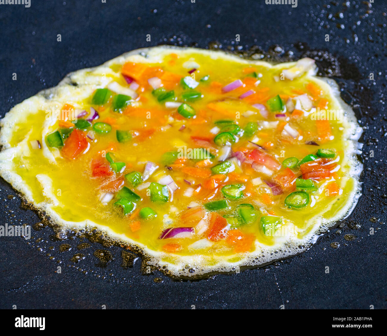 Preparing an egg omelette on a hot frying pan. Stock Photo